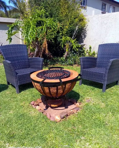 Motse boma braai alight between two garden chairs at a Pretoria home.