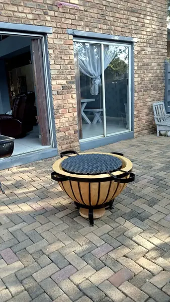 Motse boma braai with cooking grid on a brick-paved patio outside sliding doors.